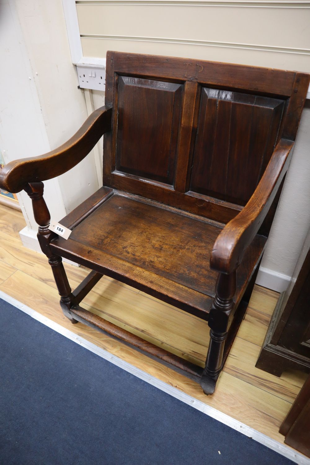 An 18th century oak panel back open armchair with wood seat,